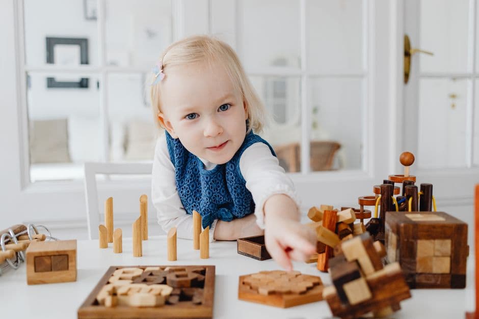 Flicka koncentrerar sig på pedagogiska träleksaker inomhus.