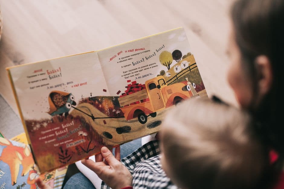 Förälder och litet barn tittar i en bilderbok tillsammans.