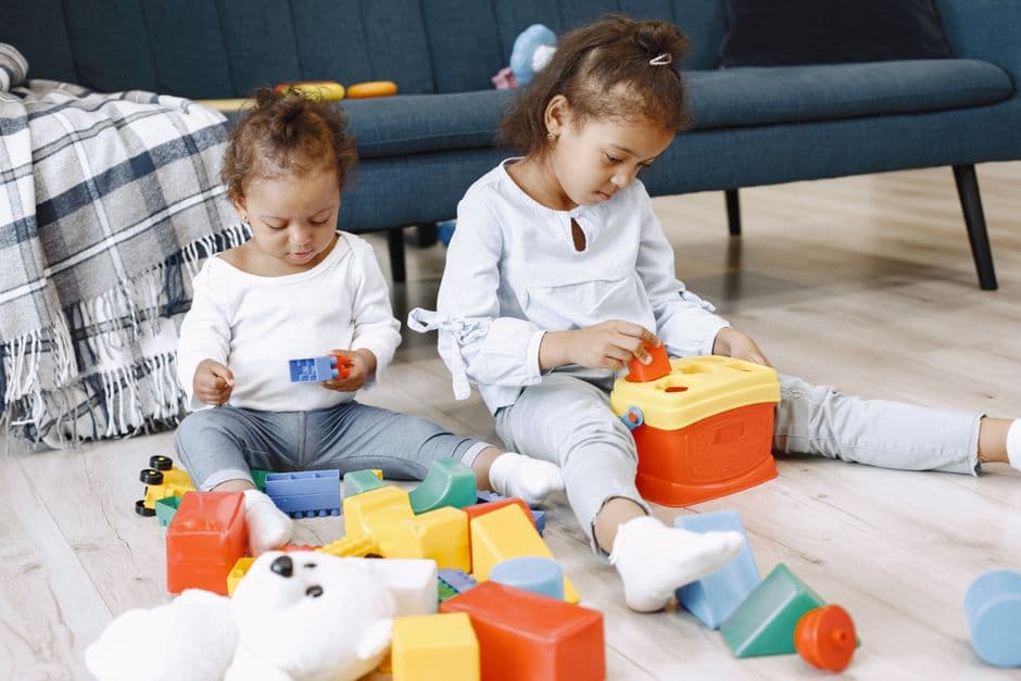Two young children enjoying playtime with colorful toys indoors on a relaxed weekend.